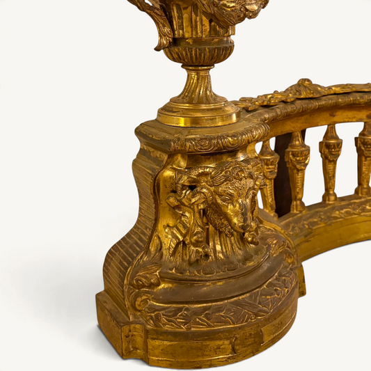 KLS Vaults Louis XVI style gilt-bronze fire fender featuring a ram's head mask, urn finial, and neoclassical motifs.