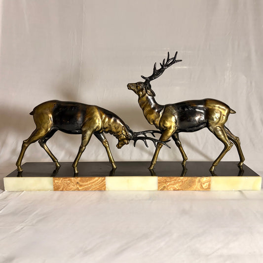 KLS Vaults Art Deco patinated metal sculpture of two rutting stags on a rouge marble and cream onyx plinth.