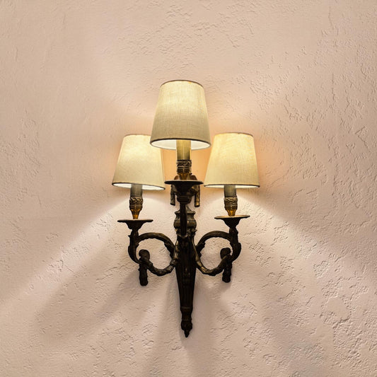 KLS Vaults pair of Louis XVI style bronze wall sconces with ram's head motifs, laurel swags, and three fabric shades.