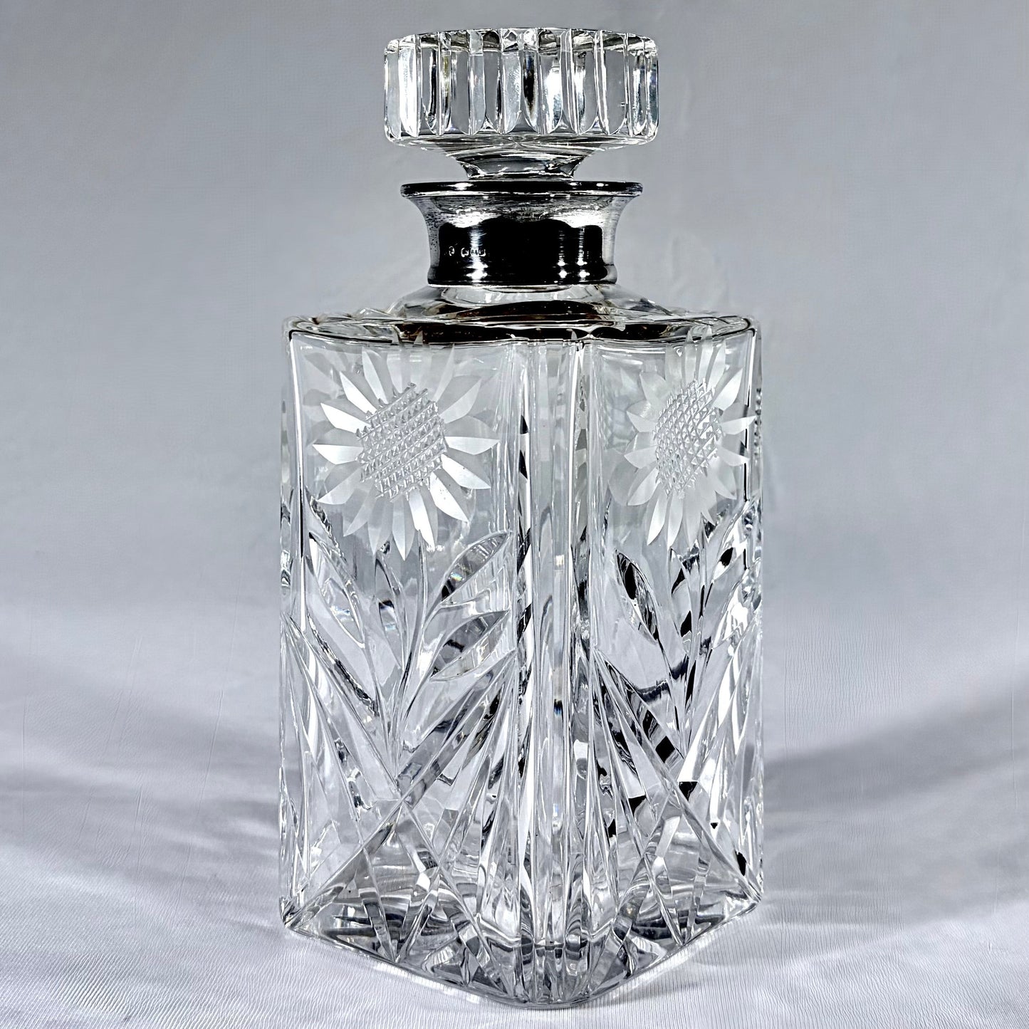 KLS Vaults mid-century cut-glass decanter with sterling silver collar, sunflower engraving, and faceted stopper.