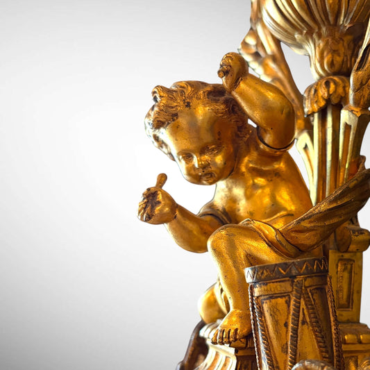 KLS Vaults 19th century gilt-bronze candelabra featuring a detailed putto figure playing a drum in ormolu finish.