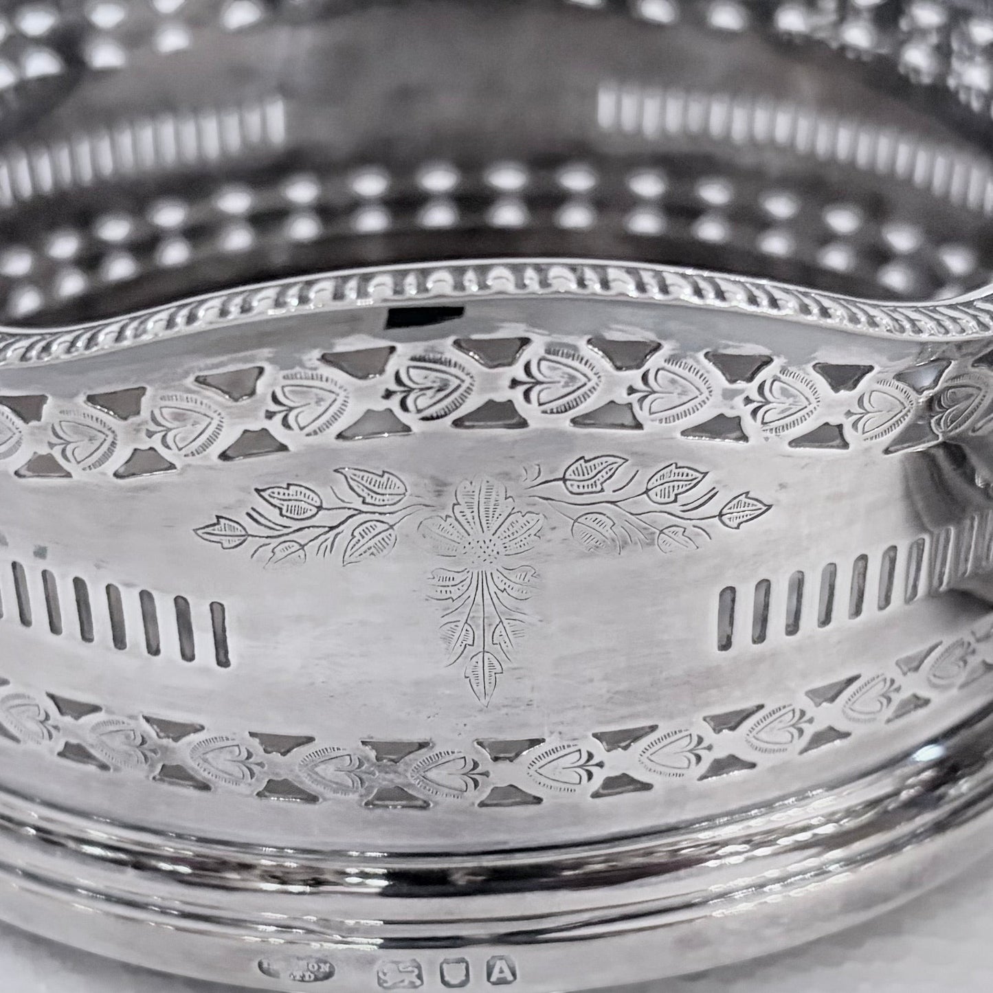 KLS Vaults pair of 1936 sterling silver wine coasters with intricate pierced fretwork and engraved foliate motifs.