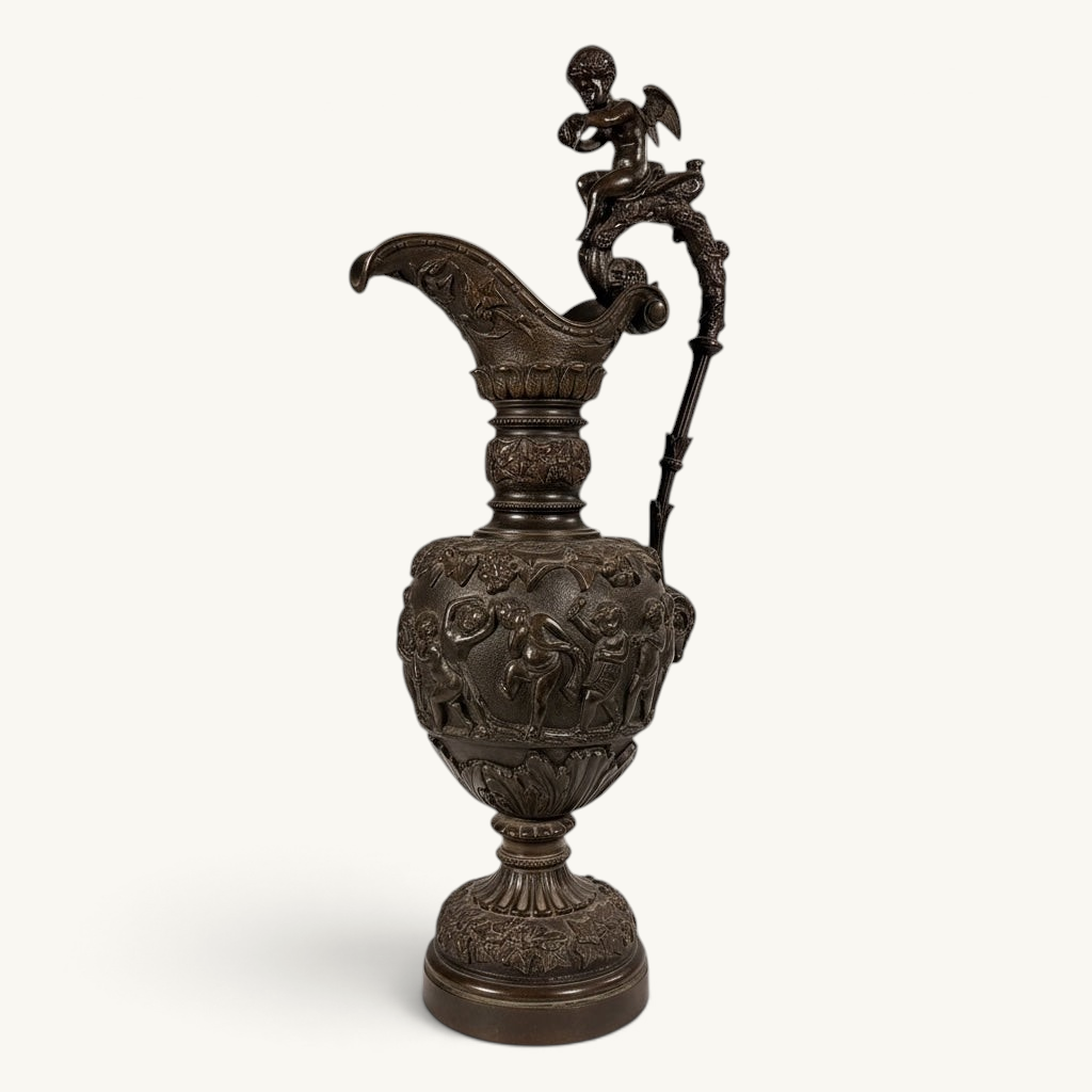 KLS Vaults 19th-century neoclassical bronze ewer with high-relief putti frieze, winged cherub finial, and brown patina.