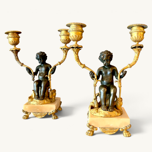 KLS Vaults pair of Napoleon III twin-light candelabra with patinated bronze putti, ormolu branches, and marble bases.