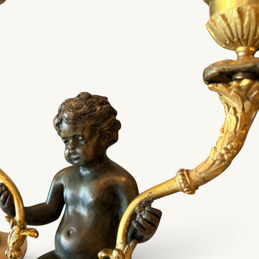 KLS Vaults Napoleon III twin-light candelabra featuring a patinated bronze putto with ornate ormolu foliate branches.
