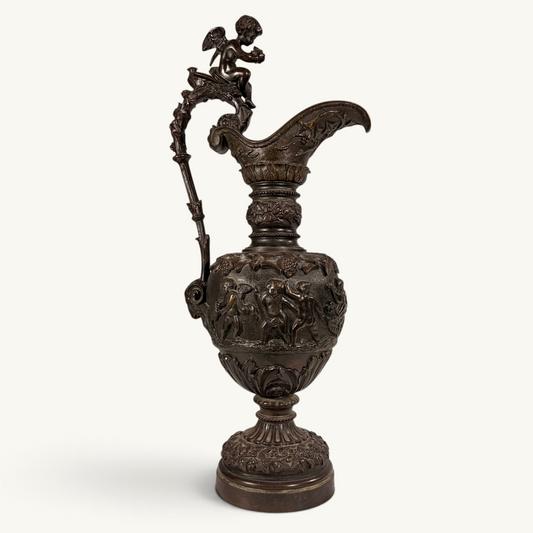 KLS Vaults 19th-century neoclassical bronze ewer with high-relief putti frieze, winged cherub finial, and brown patina.