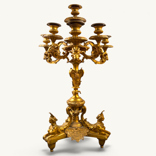 KLS Vaults 19th-century French gilt-bronze candelabrum featuring sphinxes, Roman emperor profiles, and ram-head arms.