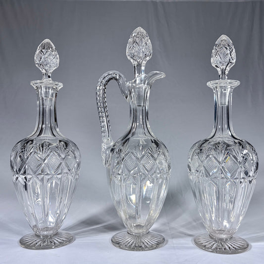 KLS Vaults 19th-century cut-glass set with two decanters and a claret jug featuring diamond-cut patterns and stoppers.