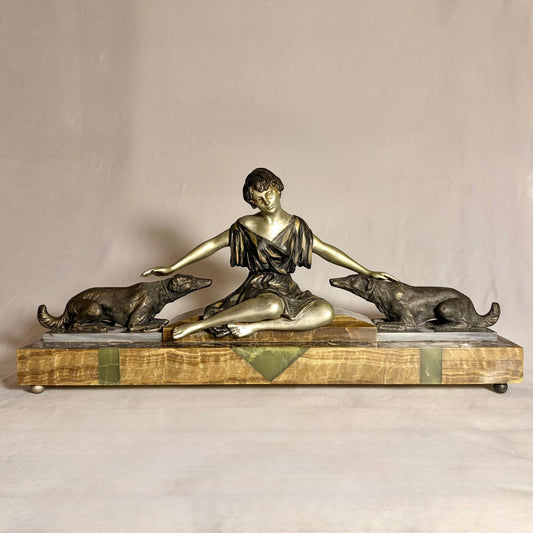KLS Vaults French Art Deco spelter sculpture of a seated woman with two hounds on a green onyx and marble plinth.
