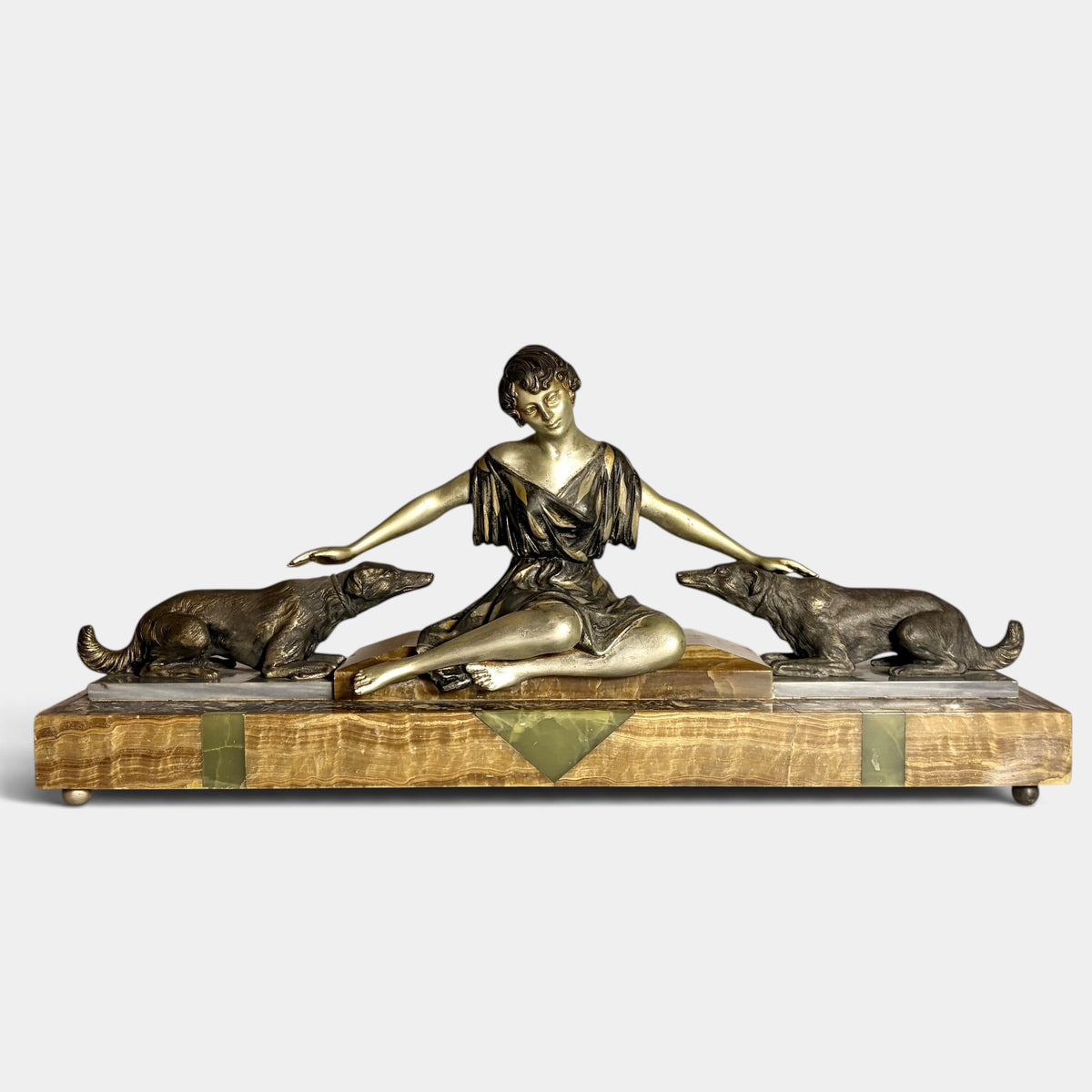 KLS Vaults Art Deco spelter figural group of a seated woman with two hounds on a decorative onyx and marble plinth.