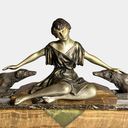 KLS Vaults Art Deco spelter figural group of a seated woman with two hounds on an onyx and marble plinth, circa 1920s.