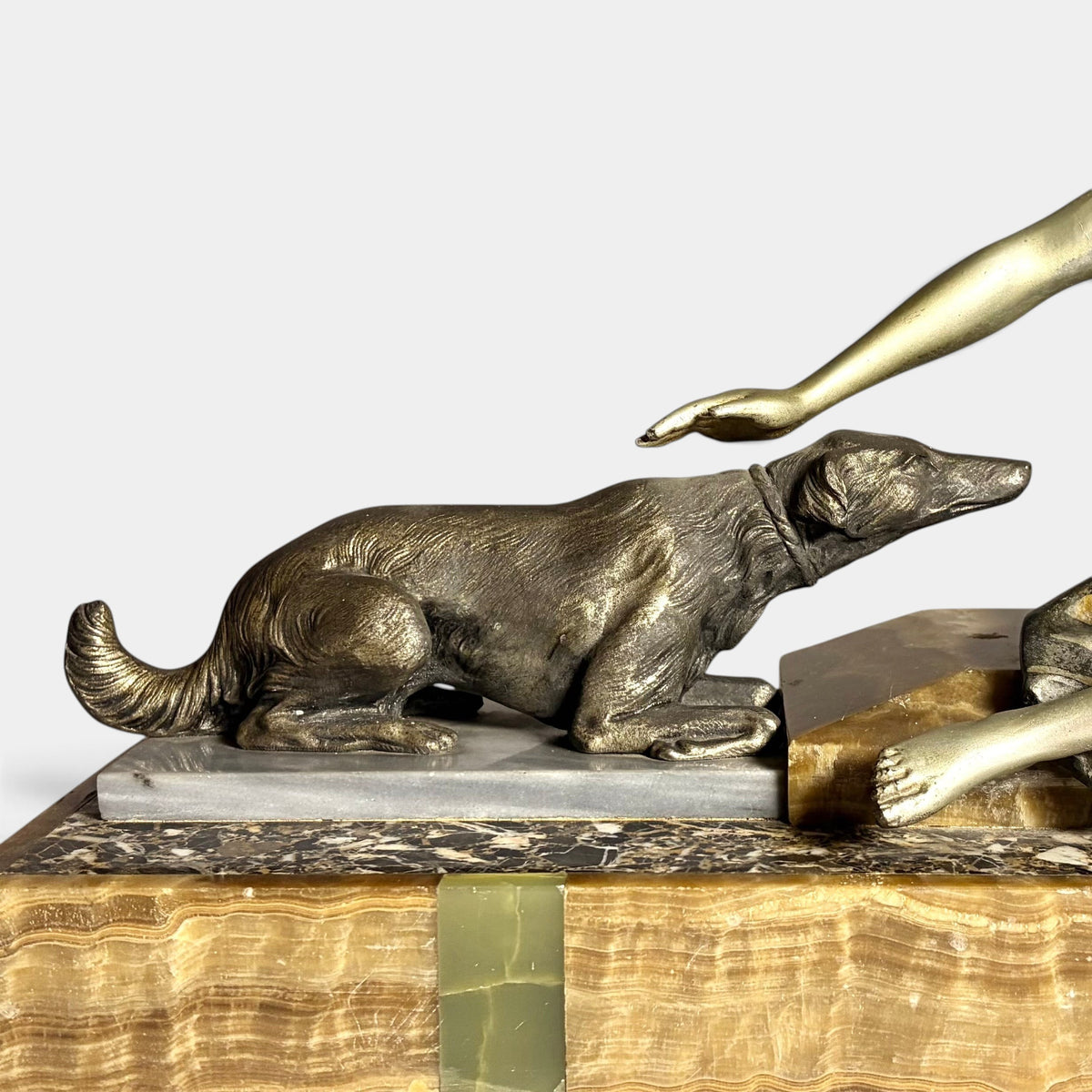 KLS Vaults Art Deco spelter sculpture of a hound resting on a decorative onyx and marble plinth, circa 1920s France.