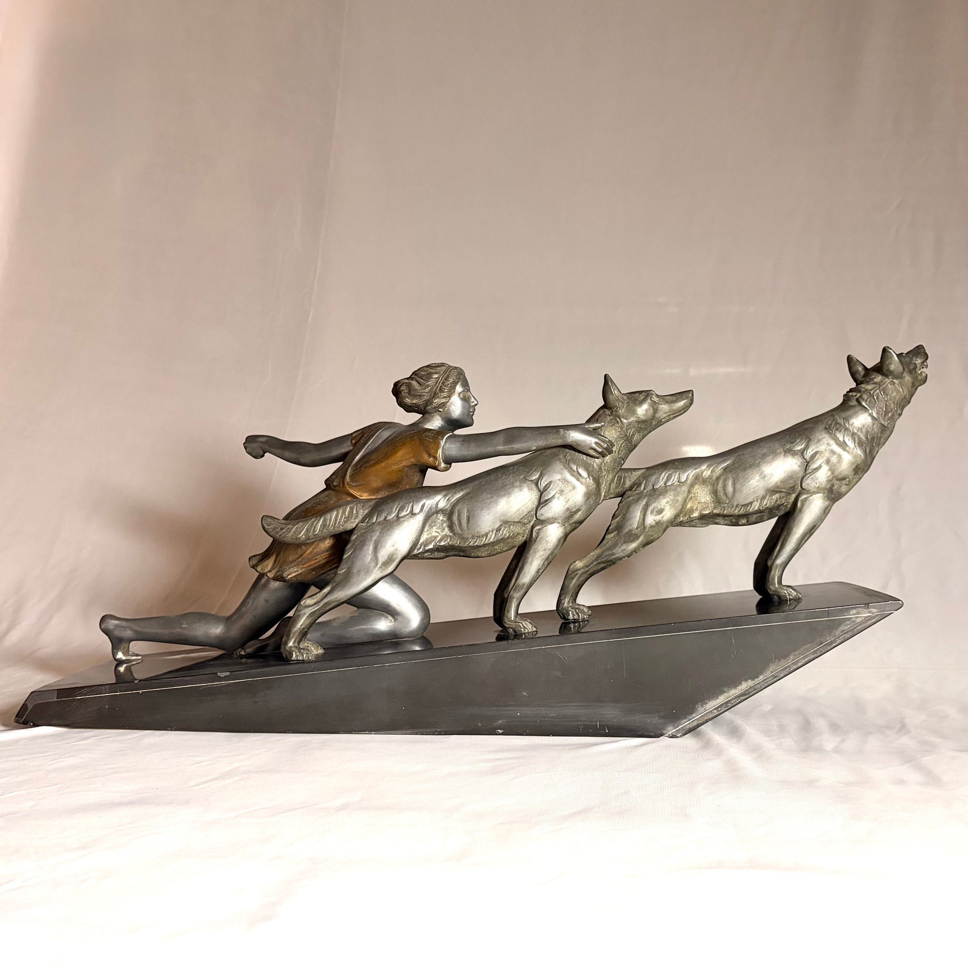KLS Vaults Art Deco silvered spelter sculpture of a kneeling maiden restraining two wolves on a black marble base.