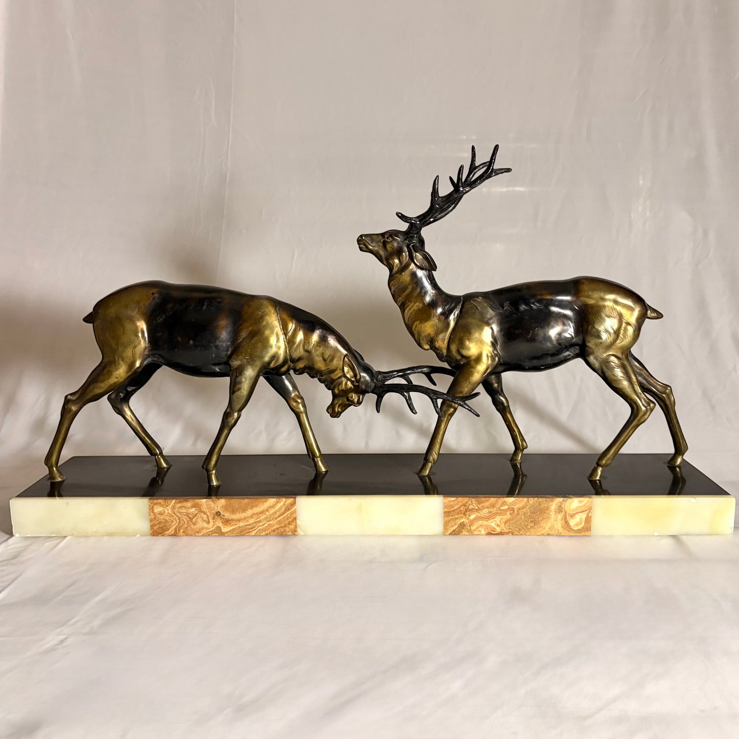 KLS Vaults Art Deco patinated metal sculpture of two rutting stags on a rouge marble and cream onyx plinth.