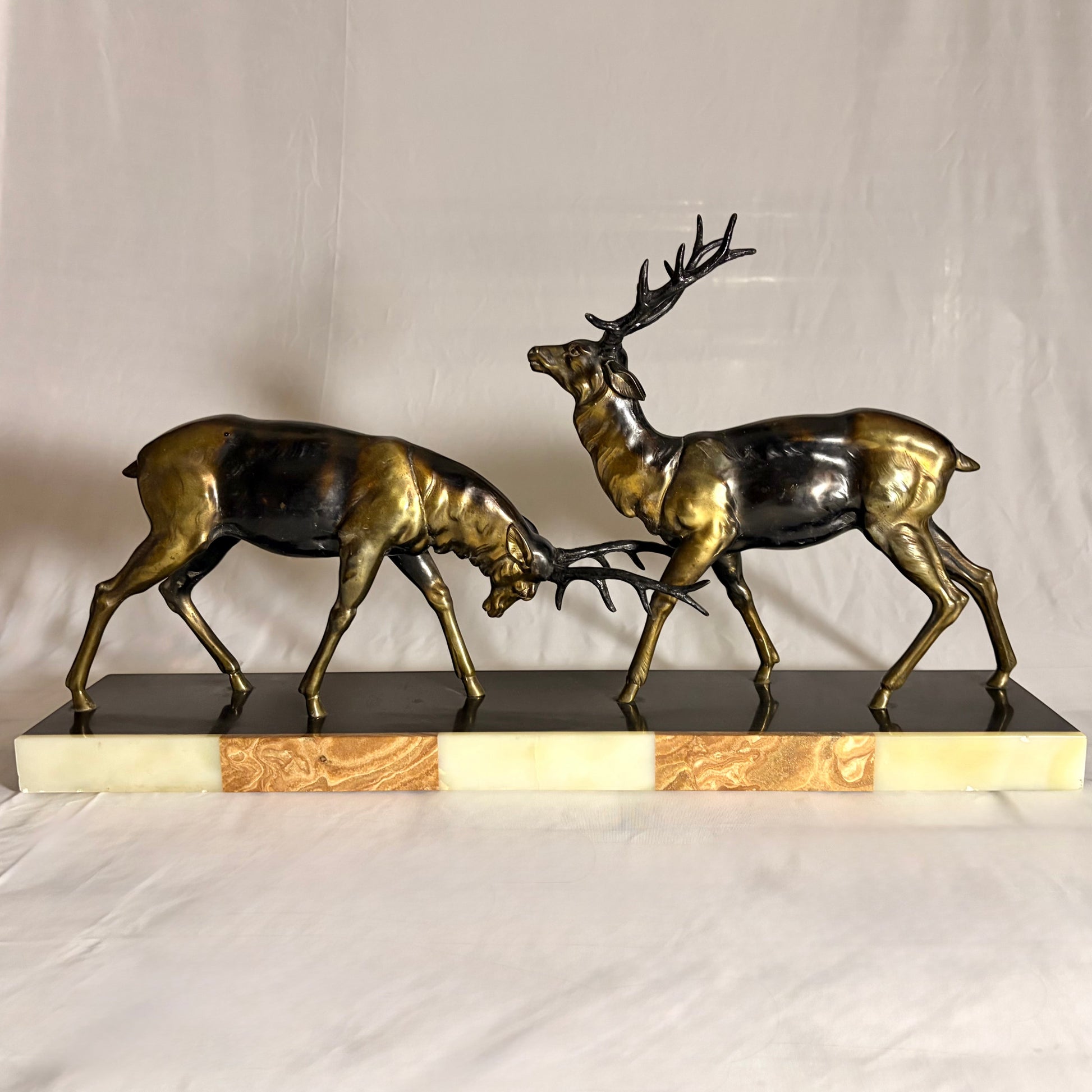 KLS Vaults Art Deco patinated metal sculpture of two rutting stags on a rouge marble and cream onyx plinth.