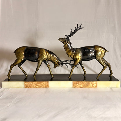 KLS Vaults Art Deco patinated metal sculpture of two rutting stags on a rouge marble and cream onyx plinth.