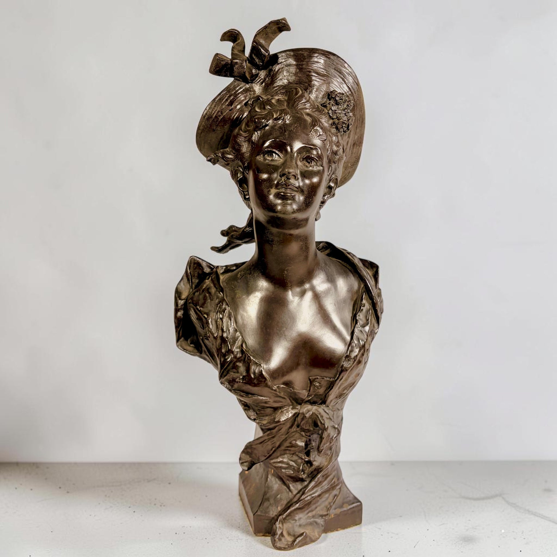 KLS Vaults patinated bronze bust of a young woman in an elaborate hat, Art Nouveau style, late 19th century.