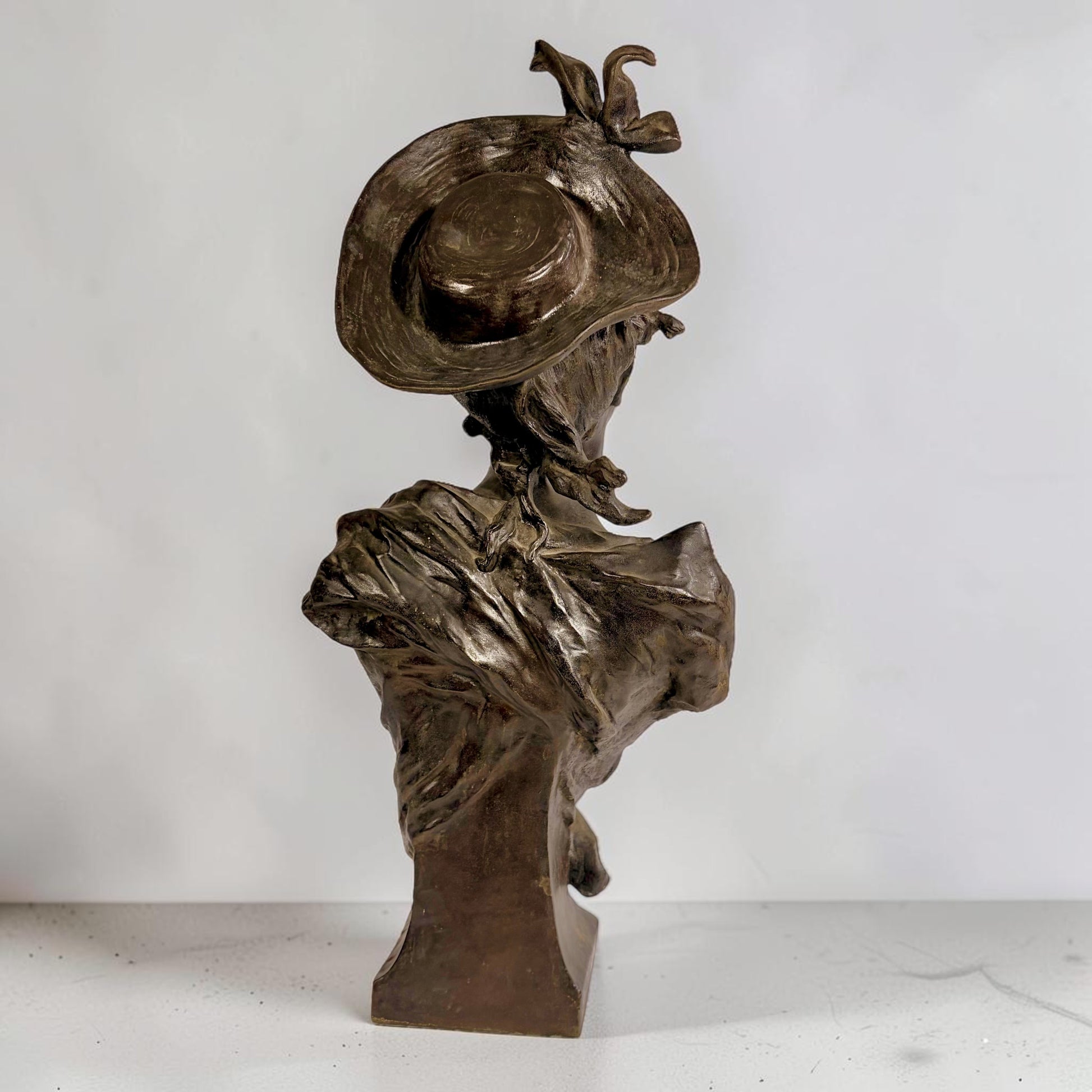 KLS Vaults Art Nouveau patinated bronze bust of a young woman wearing a wide-brimmed hat and flowing bodice, France, late 19th century.