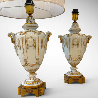 KLS Vaults pair of 1960s Italian Capodimonte porcelain table lamps with white glaze, gilt accents, and cameo motifs.