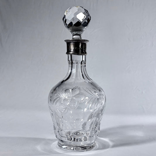KLS Vaults 1982 lead crystal decanter with sterling silver collar, wheel-engraved grapevines, and faceted stopper.