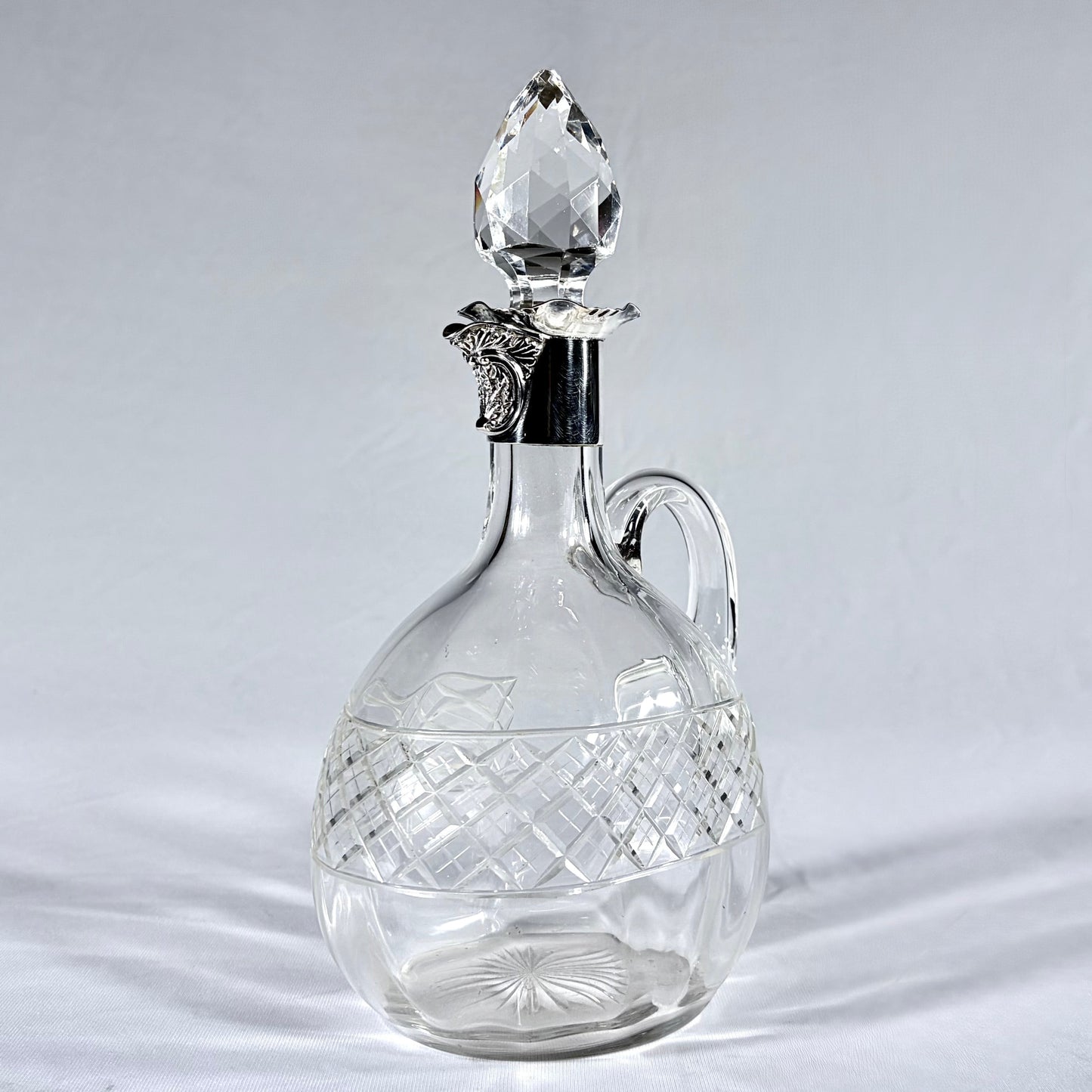 KLS Vaults Edwardian crystal claret jug with diamond-cut body, silver mount, and faceted teardrop stopper.