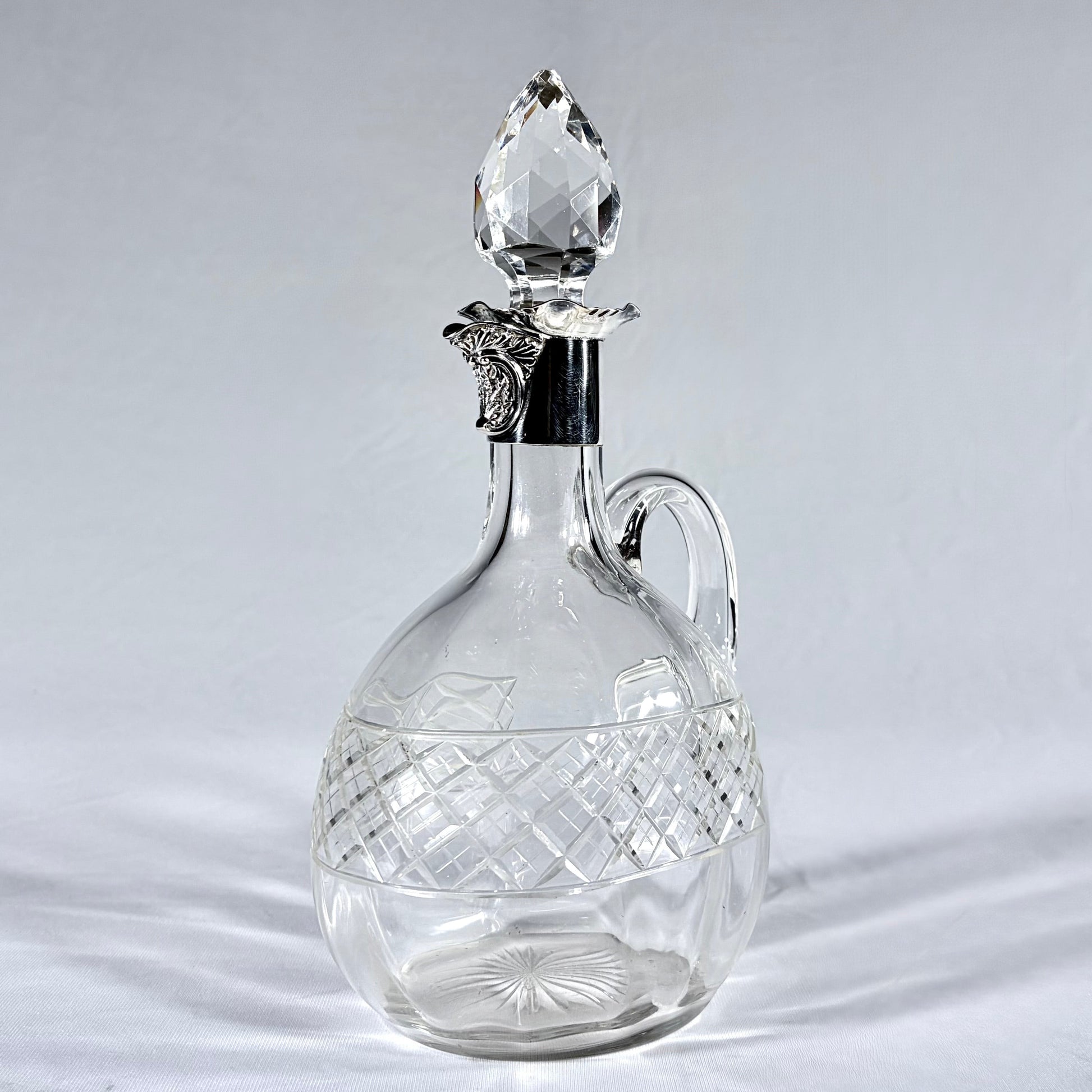 KLS Vaults Edwardian crystal claret jug with diamond-cut body, silver mount, and faceted teardrop stopper.