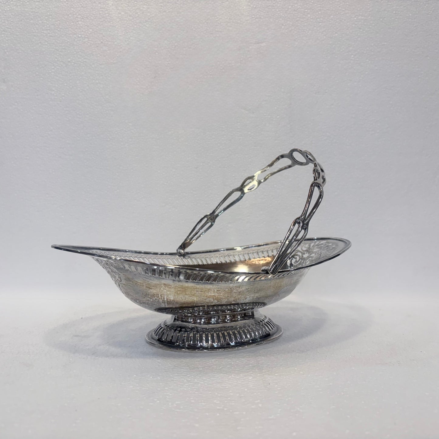 KLS Vaults Edwardian sterling silver fruit basket with pierced gallery, foliate scrollwork, and swing handle, 1905.