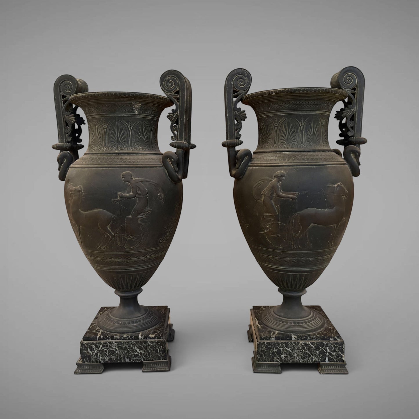 KLS Vaults pair of 19th-century French urns with dark Pompeian patina, swan-neck handles, and marble plinths.