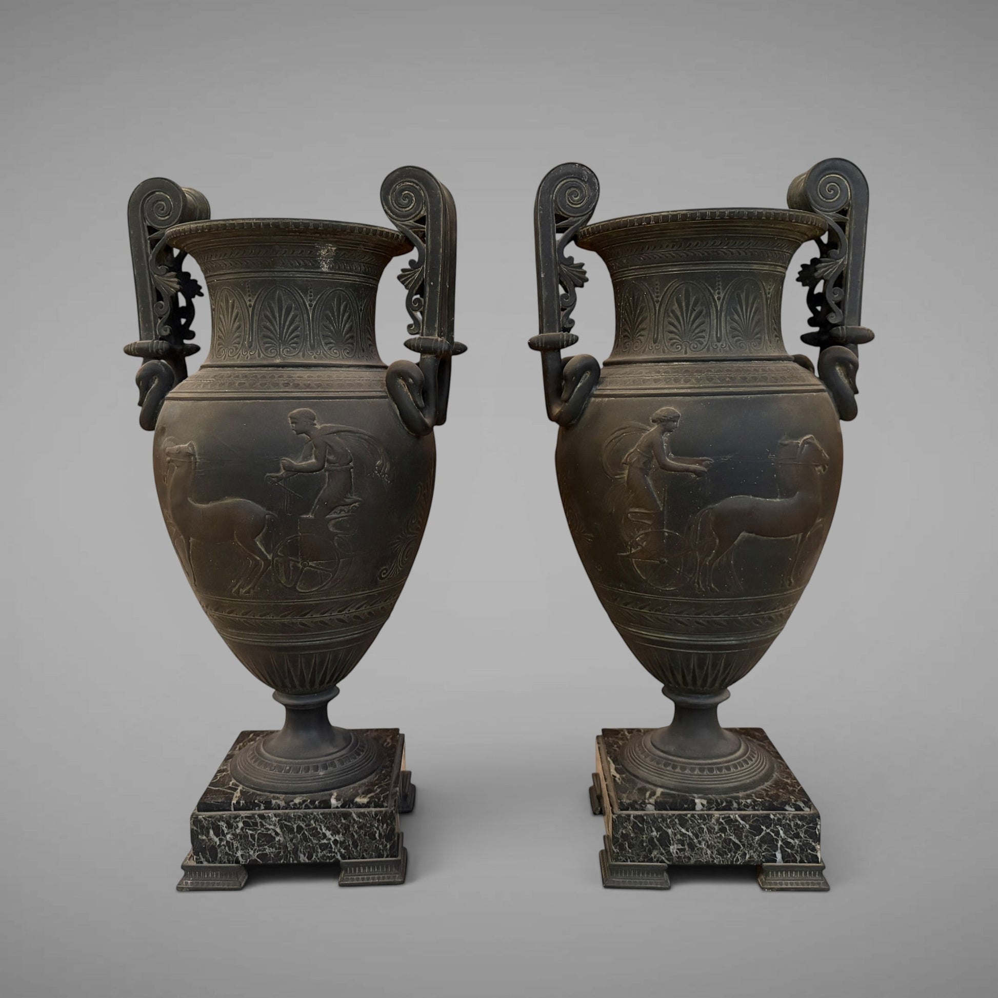 KLS Vaults pair of 19th-century French urns with dark Pompeian patina, swan-neck handles, and marble plinths.