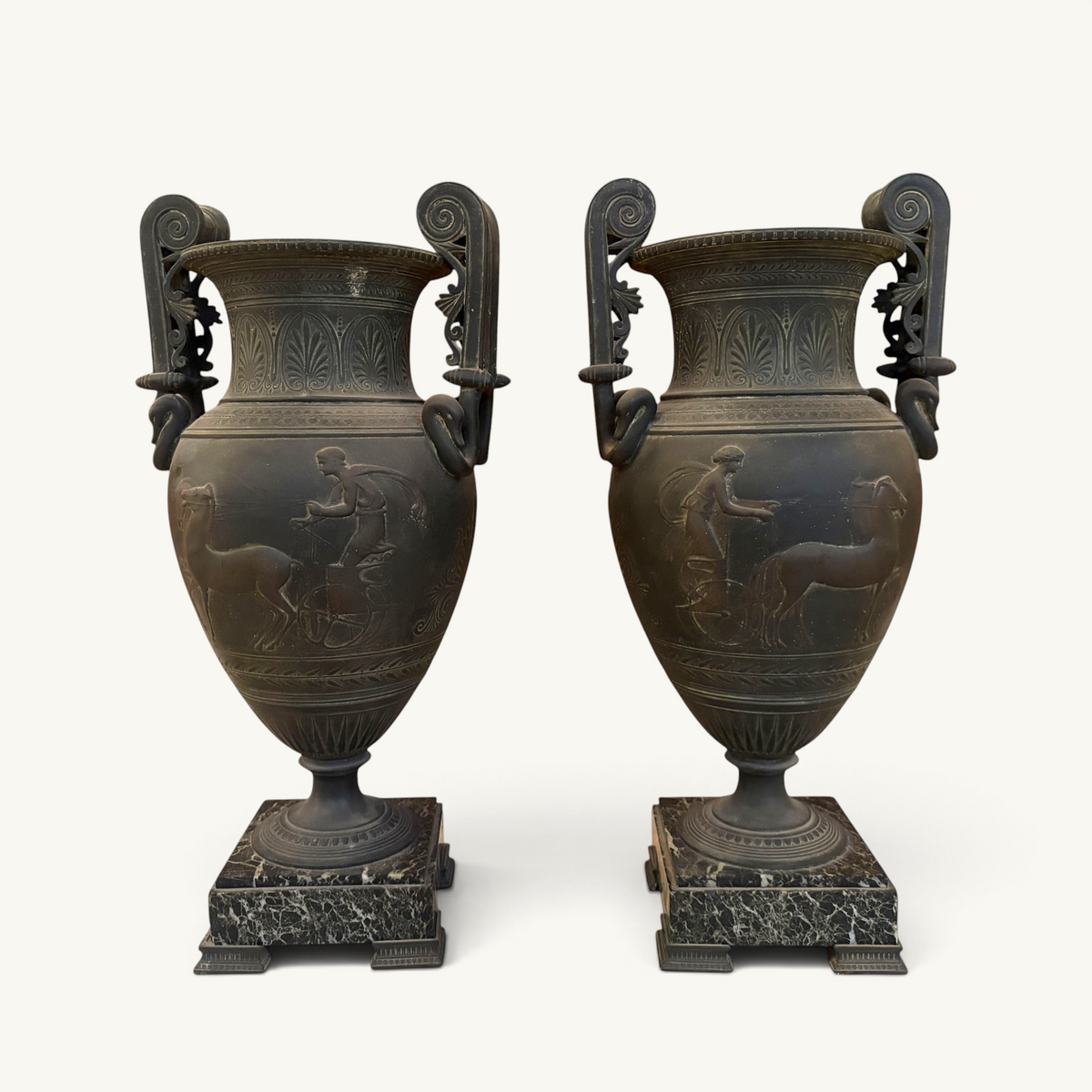 KLS Vaults pair of 19th-century French urns with dark Pompeian patina, swan-neck handles, and marble plinths.