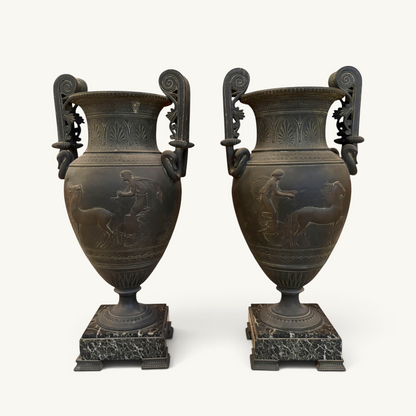 KLS Vaults pair of 19th-century French urns with dark Pompeian patina, swan-neck handles, and marble plinths.