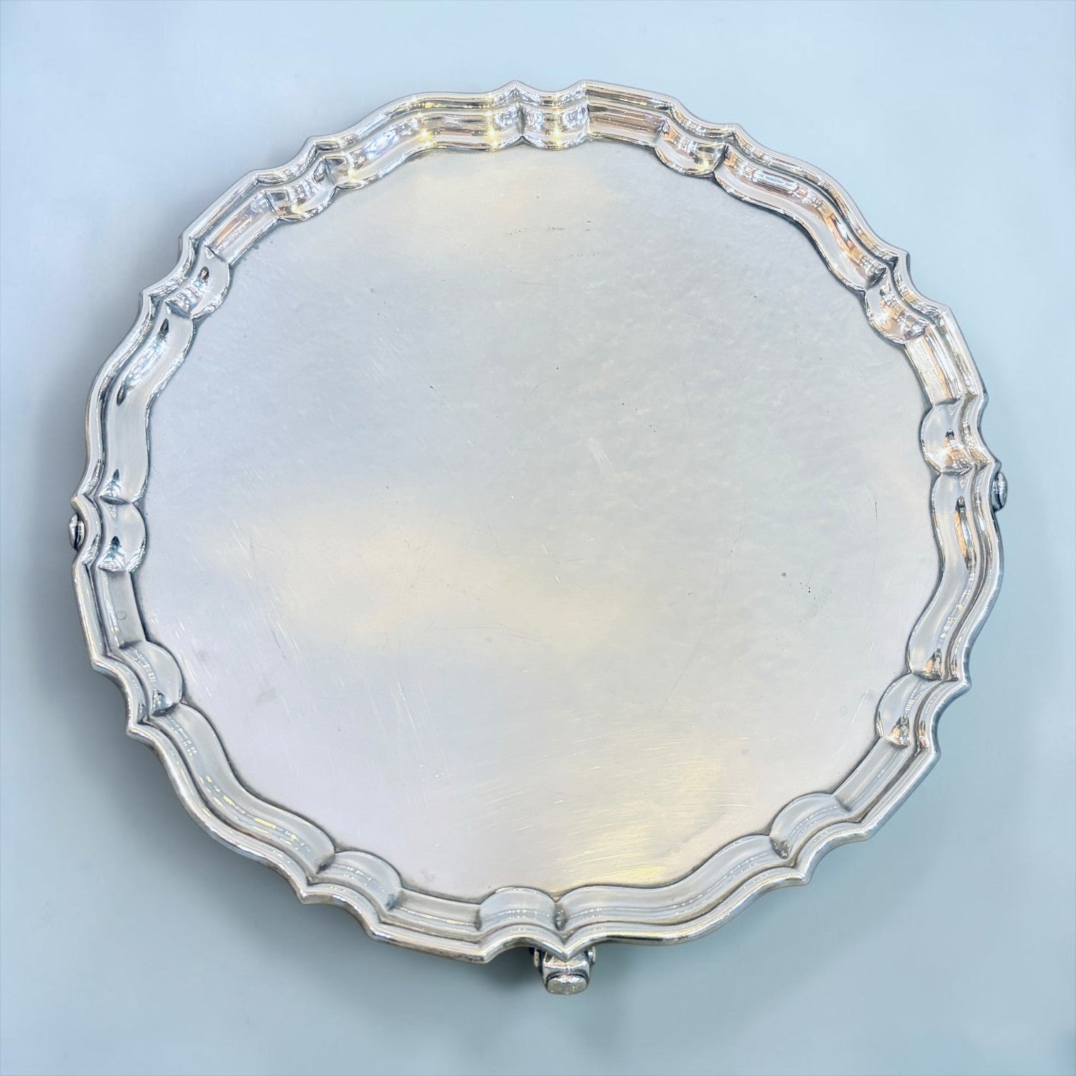 KLS Vaults George V sterling silver salver with a decorative pie-crust border and three scroll feet, London 1925.