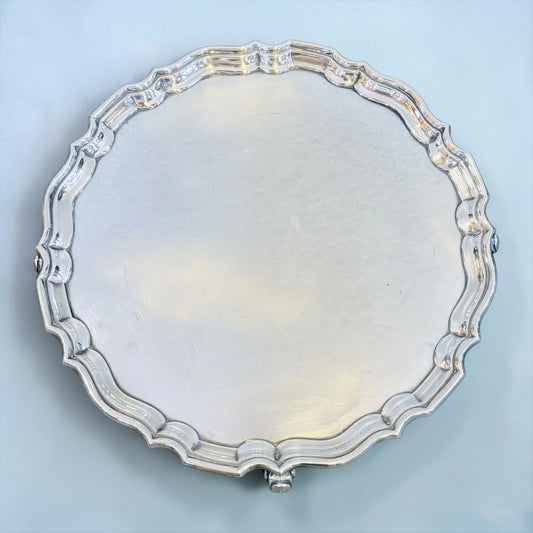 KLS Vaults George V sterling silver salver with a decorative pie-crust border and three scroll feet, London 1925.