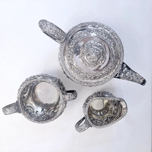 KLS Vaults 1822 sterling silver three-piece tea service with intricate repoussé floral and acanthus leaf chasing.