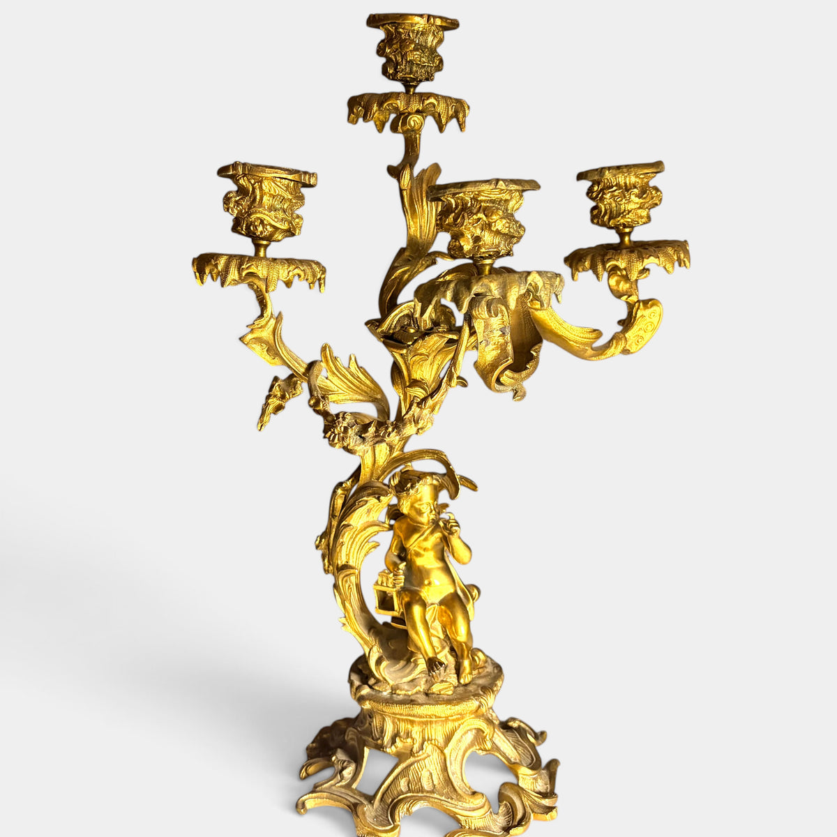 KLS Vaults 19th century French Louis XV style gilt bronze four-light candelabrum with a seated putto and rocaille base.