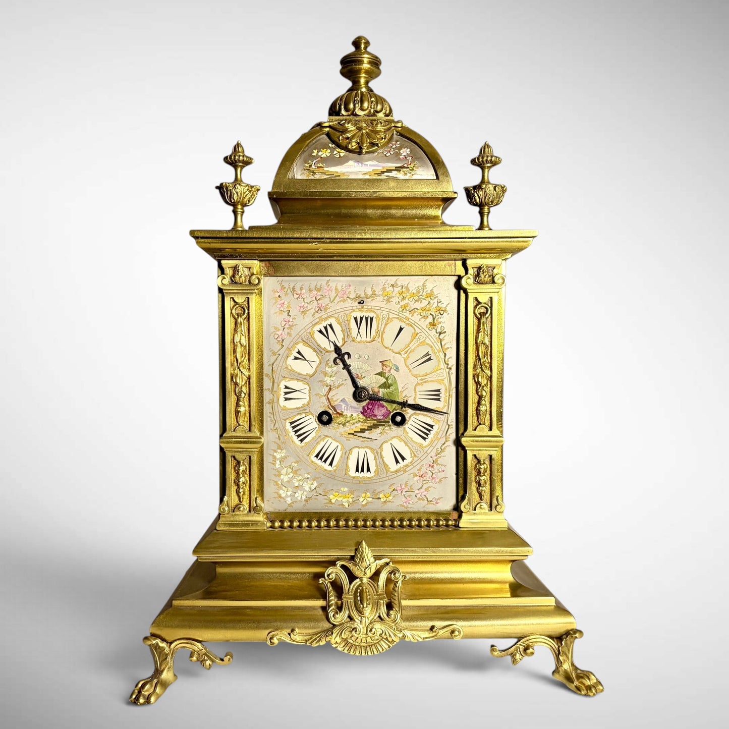 KLS Vaults French gilt-bronze mantel clock with Chinoiserie porcelain dial, arched pediment, and ornate scroll feet.