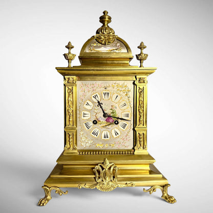 KLS Vaults French gilt-bronze mantel clock with Chinoiserie porcelain dial, arched pediment, and ornate scroll feet.