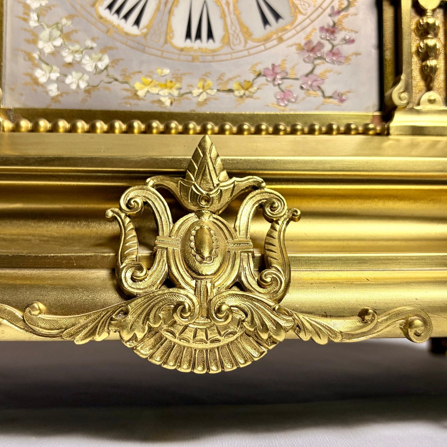 KLS Vaults French gilt-bronze mantel clock featuring ornate decorative metalwork and hand-painted chinoiserie details.