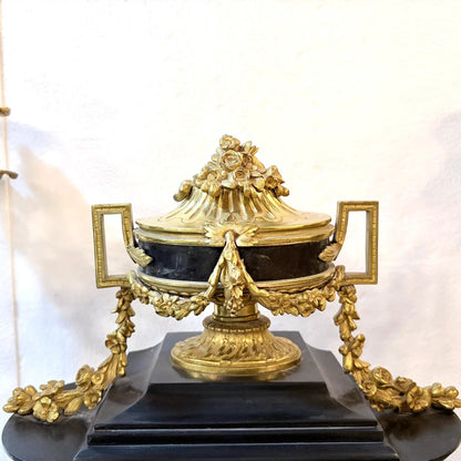 KLS Vaults Louis XVI Revival mantel clock featuring a black marble urn with ornate gilt-bronze floral swags.