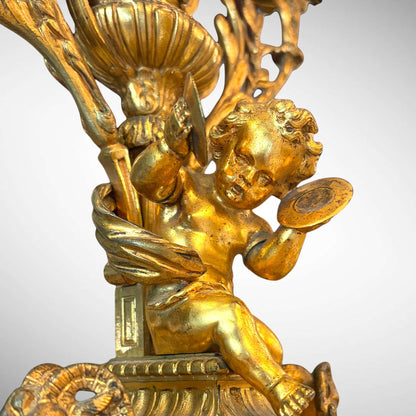 KLS Vaults 19th-century gilt-bronze candelabra featuring a detailed putto playing cymbals on a neoclassical base.