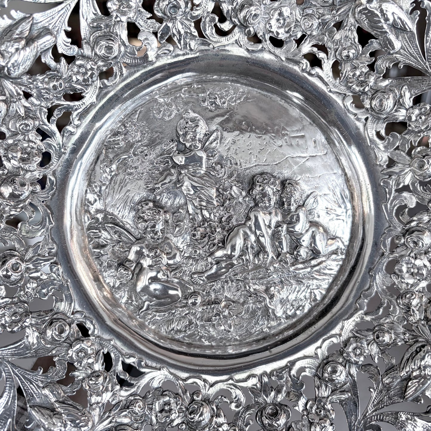 KLS Vaults 19th-century Hanau silver tazza with intricate pierced floral scrolls and a repoussé putti medallion.