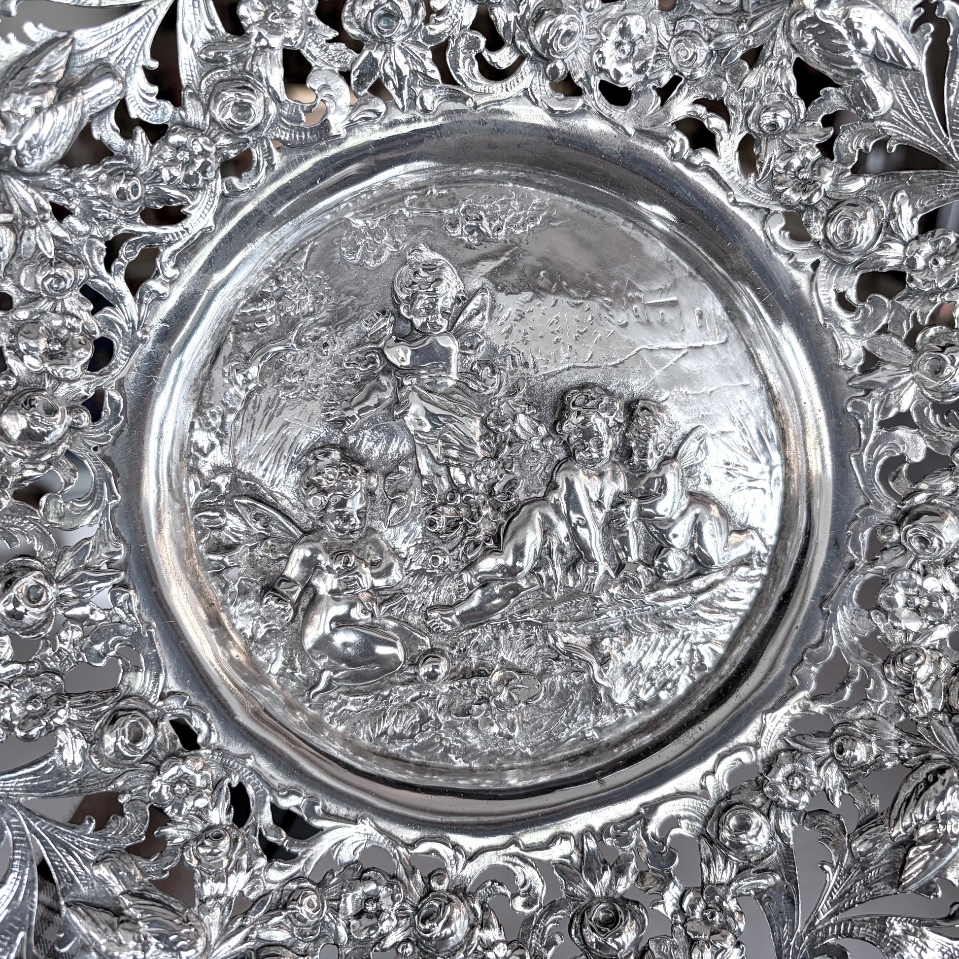 KLS Vaults 19th-century Hanau silver tazza with intricate pierced floral scrolls and a repoussé putti medallion.