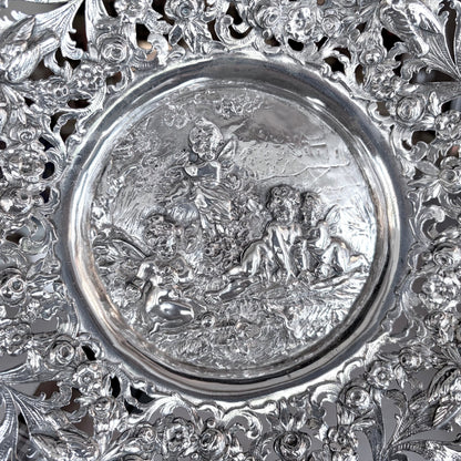 KLS Vaults 19th-century Hanau silver tazza with intricate pierced floral scrolls and a repoussé putti medallion.