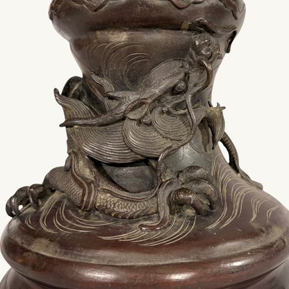 KLS Vaults Japanese Meiji period bronze vase featuring a detailed relief sculpture of a dragon coiling over waves.