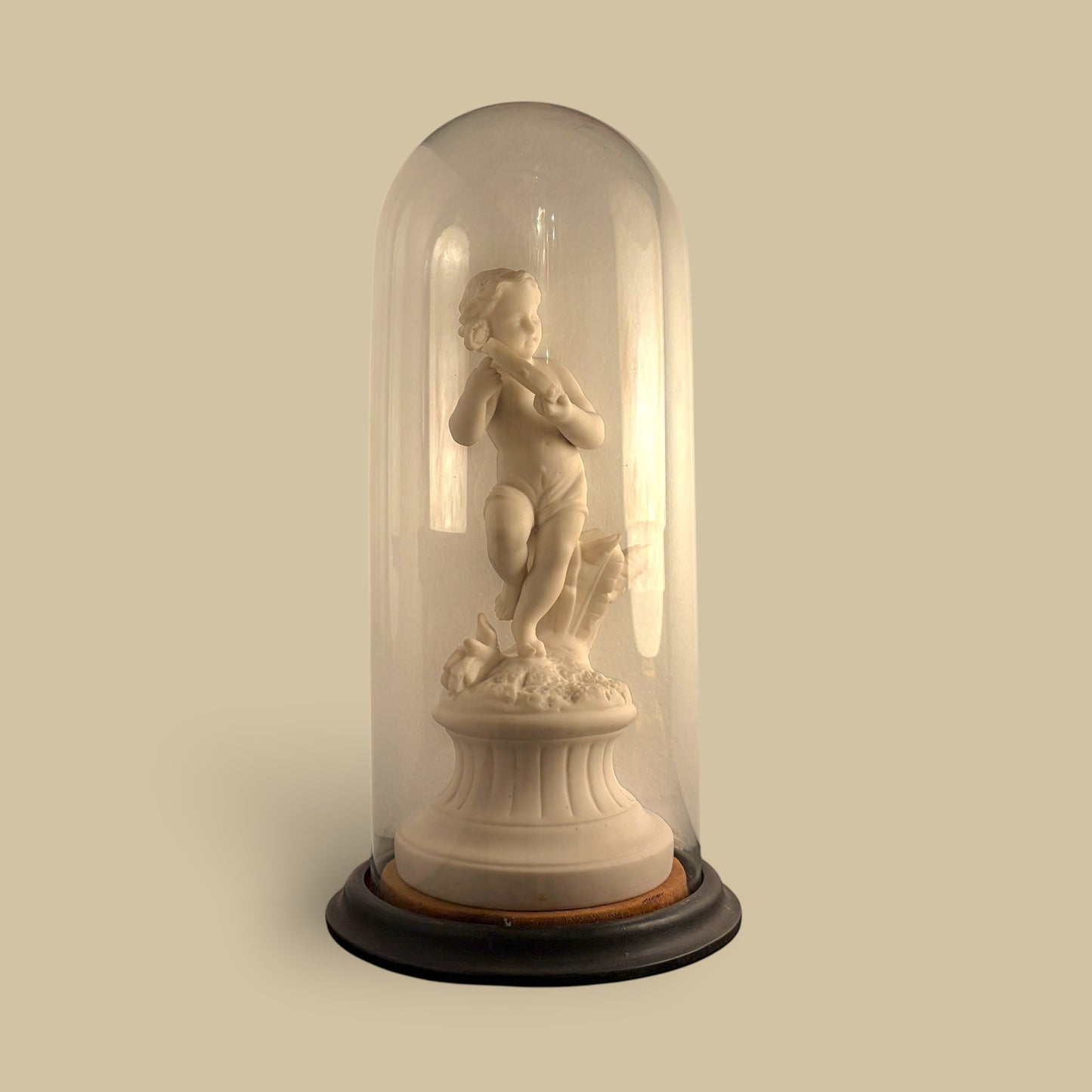 KLS Vaults 19th-century Parian ware putto statue with tambourine, displayed under a glass cloche on an ebonised base.