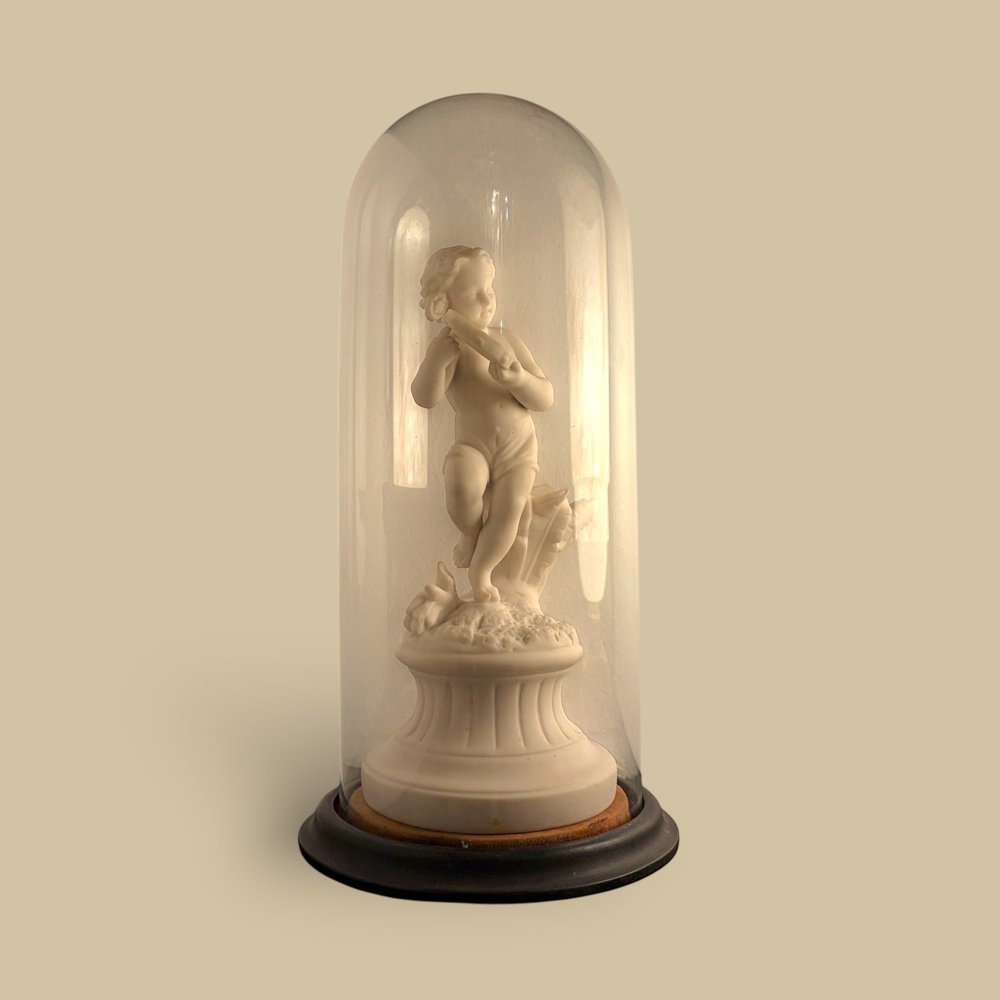 KLS Vaults 19th-century Parian ware putto statue with tambourine, displayed under a glass cloche on an ebonised base.