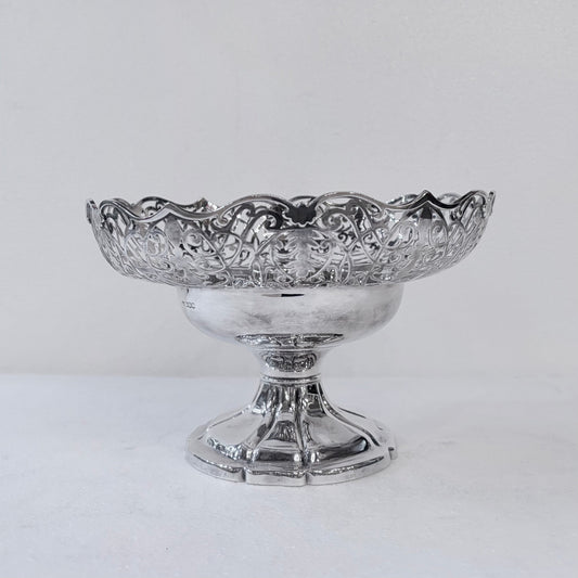 KLS Vaults 1935 sterling silver centerpiece bowl with intricate pierced scrollwork and a scalloped rim on a pedestal.