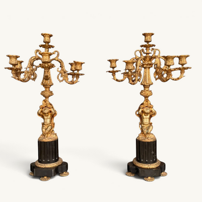 KLS Vaults pair of 19th-century French Rococo gilt bronze five-light candelabra featuring putti on black marble bases.