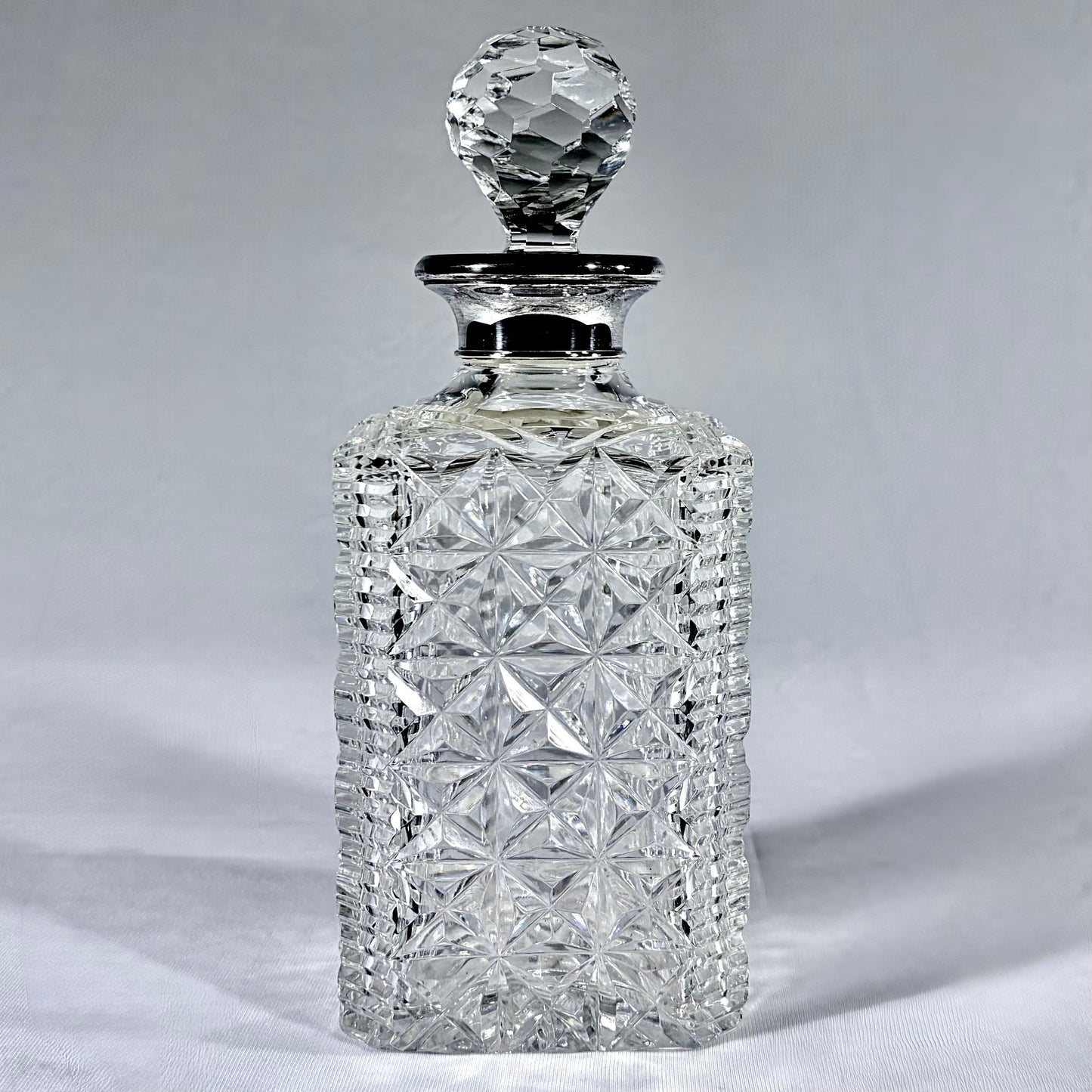 KLS Vaults Elizabeth II silver-mounted cut-glass decanter with diamond and star patterns and a faceted glass stopper.