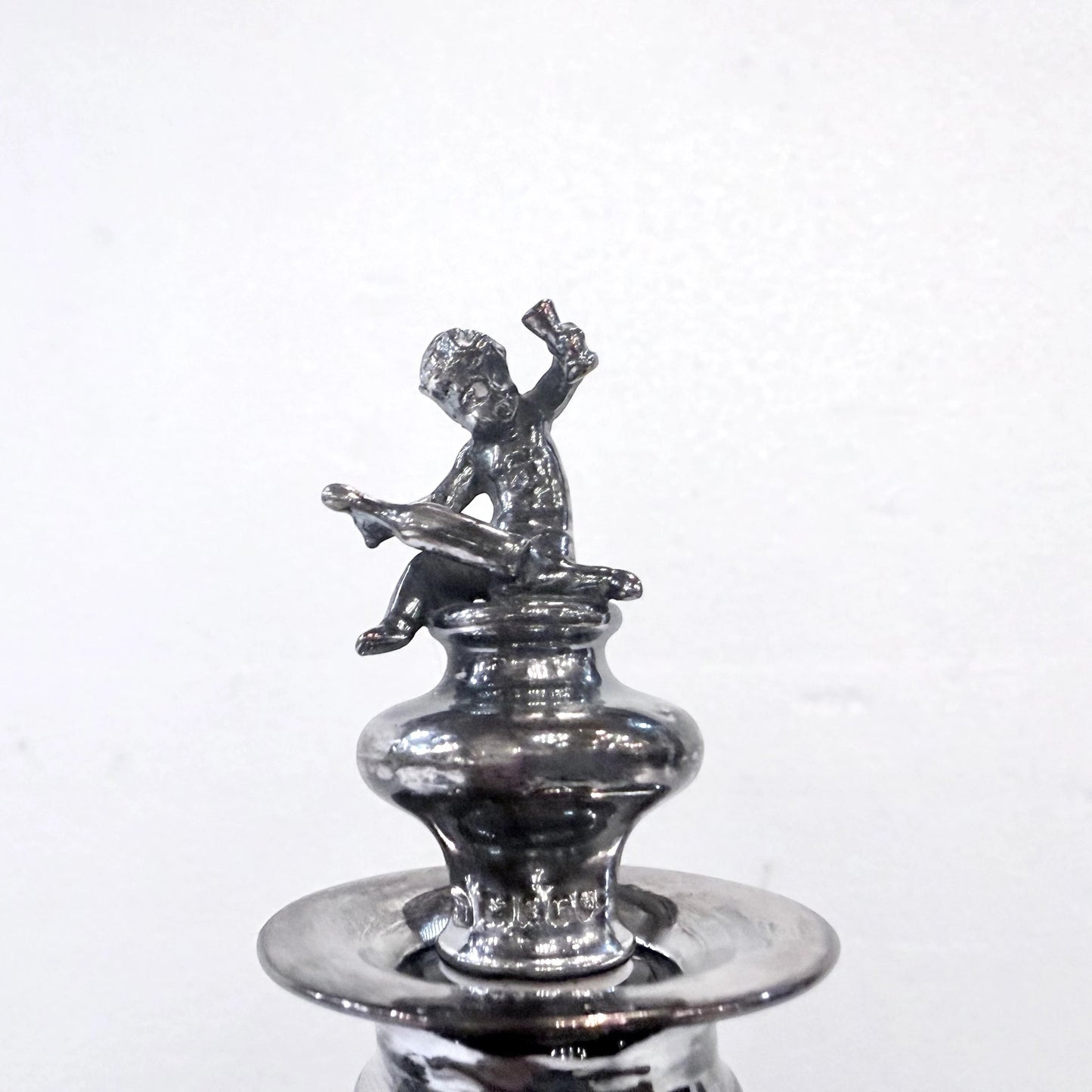 KLS Vaults antique 1902 sterling silver stopper featuring a seated putto finial on an Edwardian glass decanter